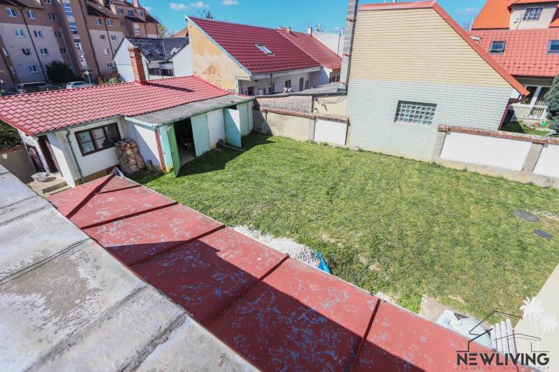 The courtyard of a family house on Hviezdoslavova Street in Piešťany with a lawn and a shelter.