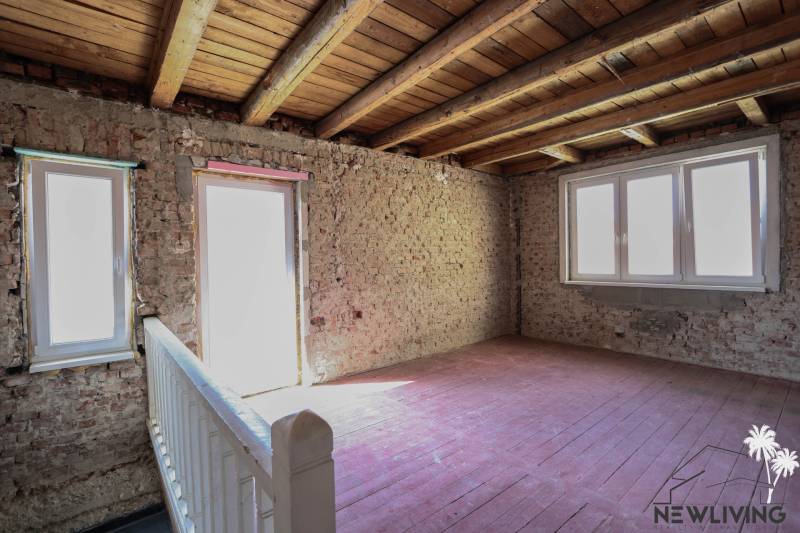 The interior of a family house with bare brick walls, a wooden ceiling, and floor.