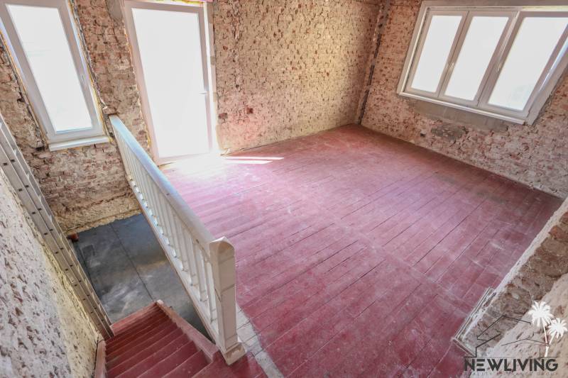 A staircase and brick walls in a family house with large windows and flooring.