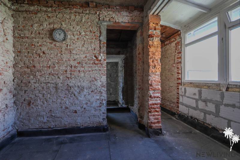 Unplastered brick walls and a simple interior with a window in a family house.