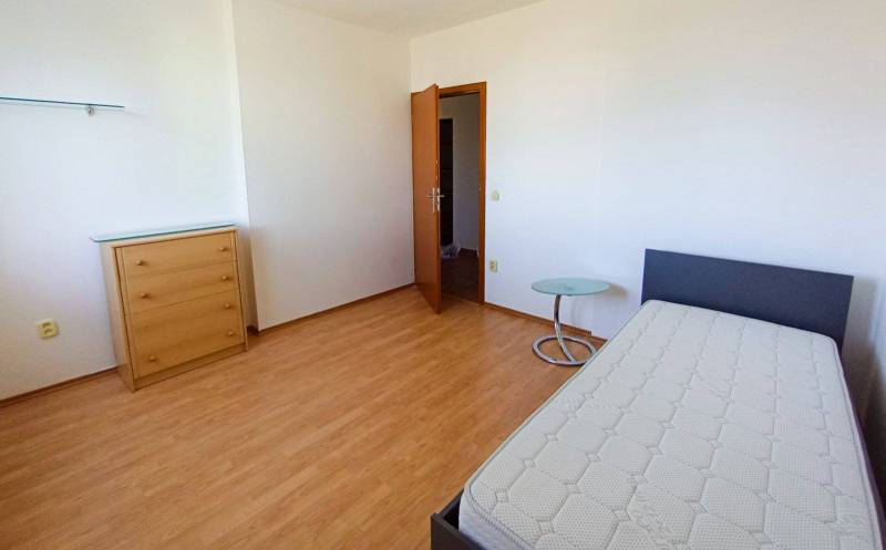 A room in a 3-room apartment, with a bed, a dresser, and a floor with a wooden decor.