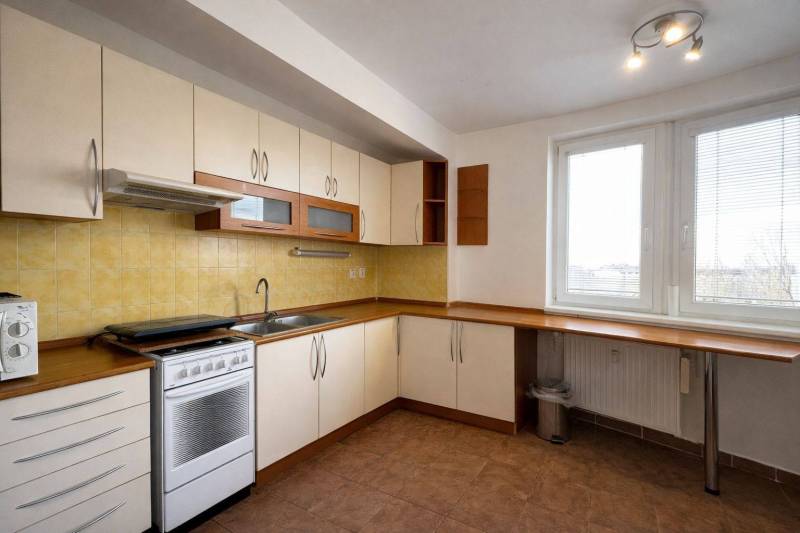 A kitchen in a 3-room apartment with white cabinets, yellow tiles, and a gas stove.