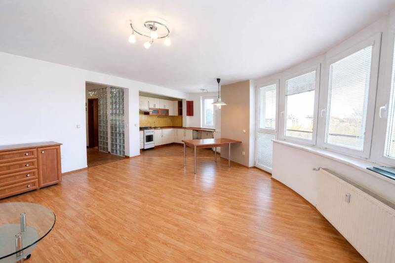 Spacious living area with kitchen and wood-patterned flooring in a 3-room apartment.