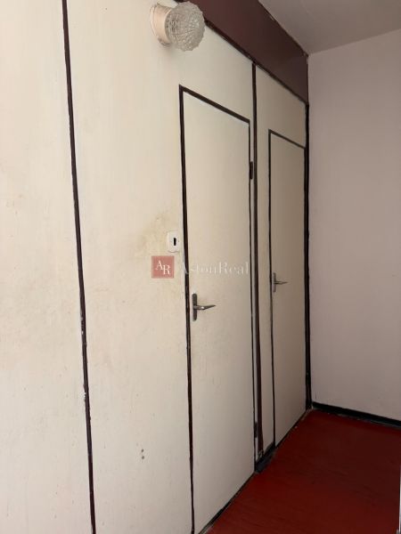 White doors in a 2-room apartment with a dark floor and a wall lamp.