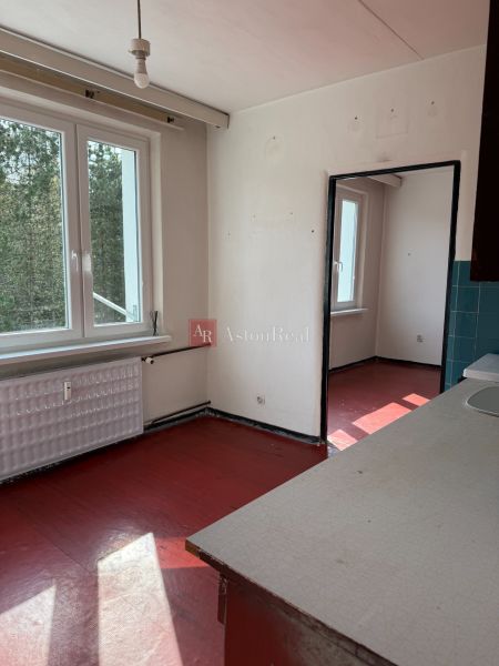 A kitchen in a 2-room apartment with a red floor and a large window.