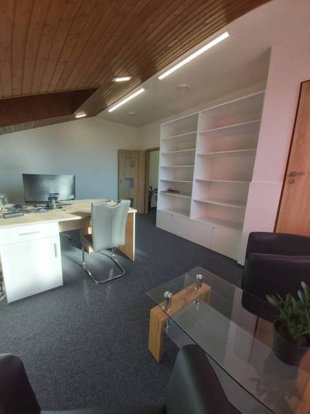 Offices with white shelves, wooden ceiling, desk, and conference table.