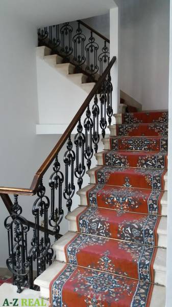 A staircase with wrought iron railing and a colorful carpet in the offices.
