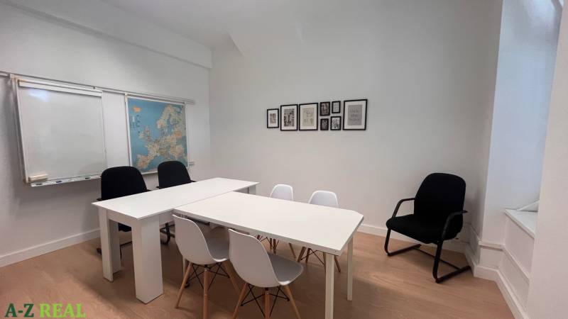 An office with white furniture, a map of Europe on the wall, and a floor with a wooden decor.