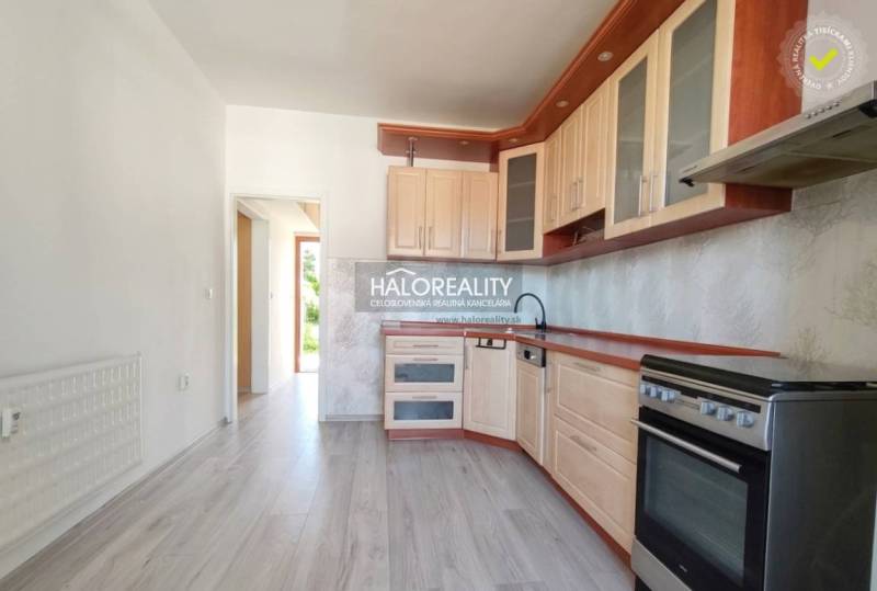 A kitchen in a 3-room apartment with a wooden decor floor and light furniture.