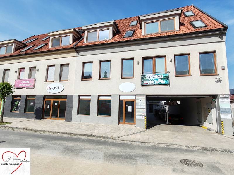 Commercial premises in Trnava with a white facade, red roof, and advertising signs.