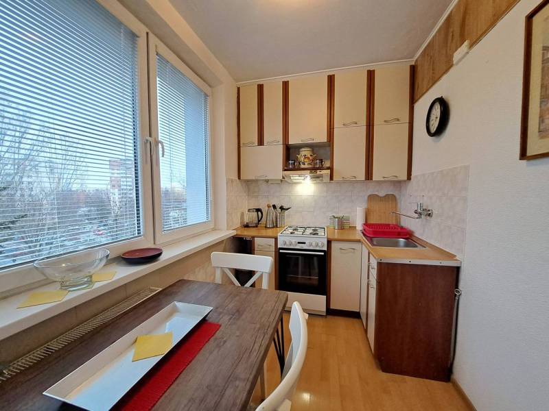 A kitchen in a 2-room apartment with a gas stove and a wooden decor floor.