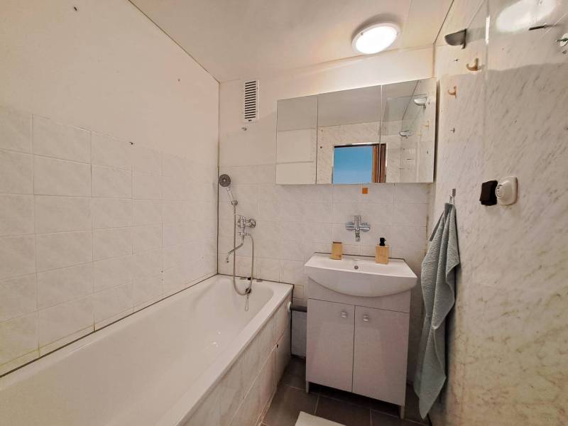 Bathroom in a 2-room apartment with a bathtub, sink, and mirror.