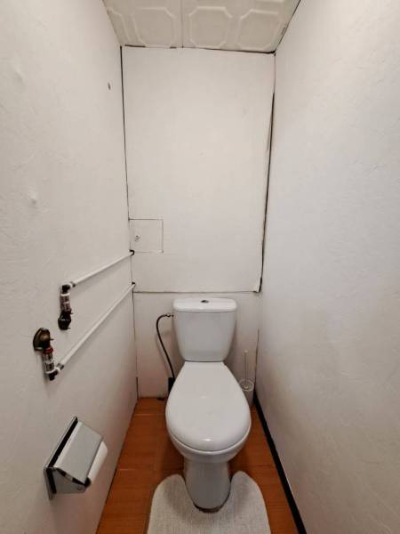 A bathroom with a toilet and a wooden decor floor in a 2-room apartment.