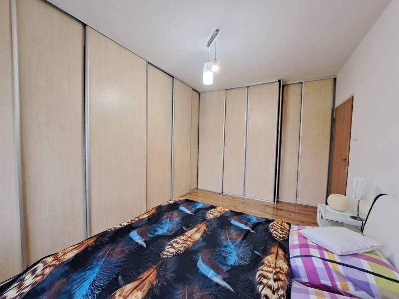 A bedroom with a large built-in wardrobe and a bed in a 2-room apartment.