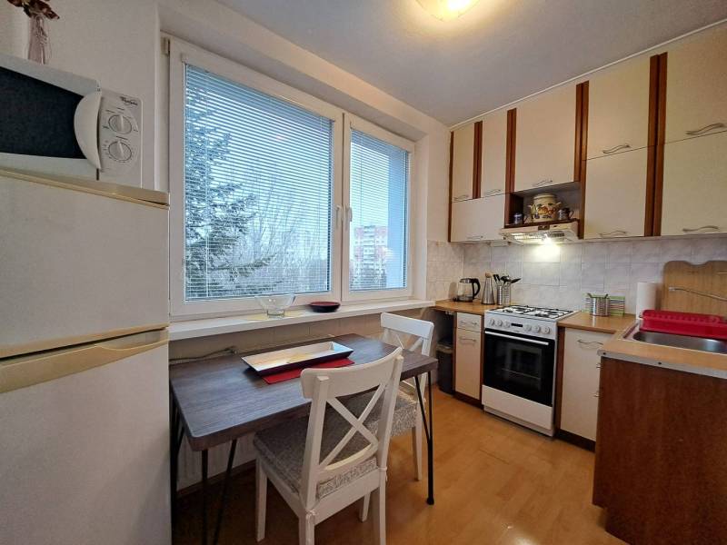 A kitchen in a 2-room apartment with a wooden decor floor and a view.