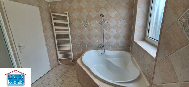 A bathroom with a separate bathtub and tiles in a 3-room apartment.