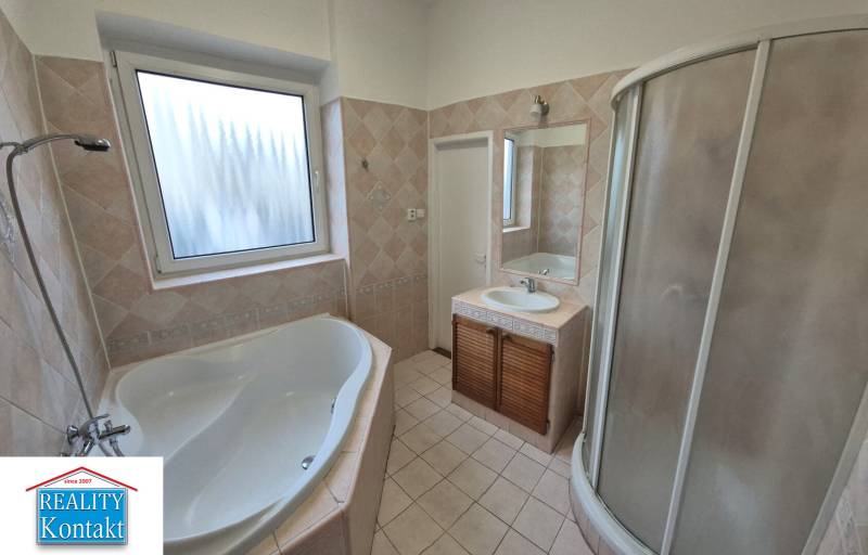 A bathroom with a bathtub and shower in a 3-room apartment, tiles with a subtle pattern.
