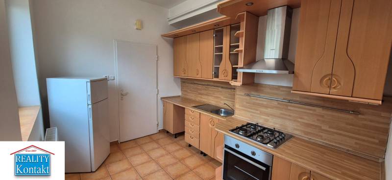 A kitchen in a 3-room apartment with a wooden decor kitchen unit and appliances.