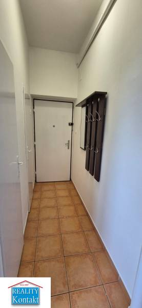 A hallway with ceramic tiles and a coat rack wall in a 3-room apartment.