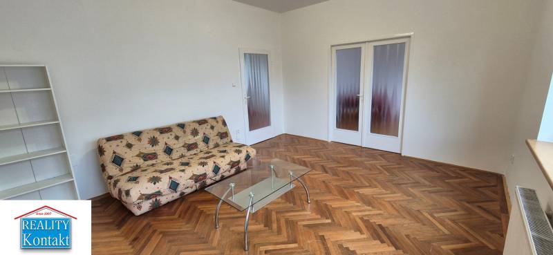 Living room in a 3-room apartment with a sofa and a glass table, floor with wood decor.