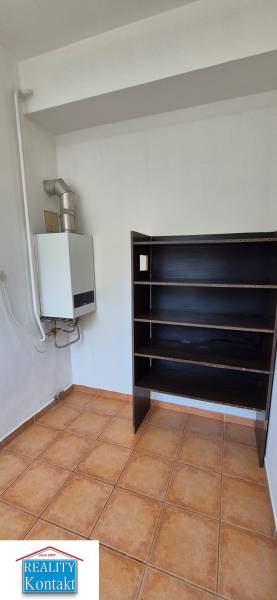 Boiler and shelf in the space of a 3-room apartment, with tiles on the floor.