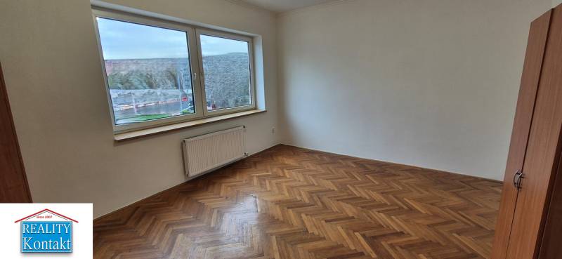 A spacious room with a large window and a wooden decor floor in a 3-room apartment.