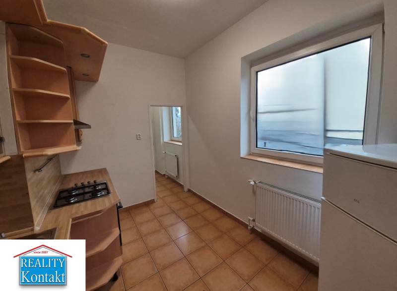 A kitchen in a 3-room apartment with tiles and a large window, light walls, wooden shelves.