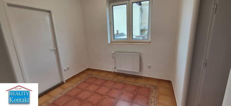 A room in a 3-room apartment with tiles, white walls, and a window.