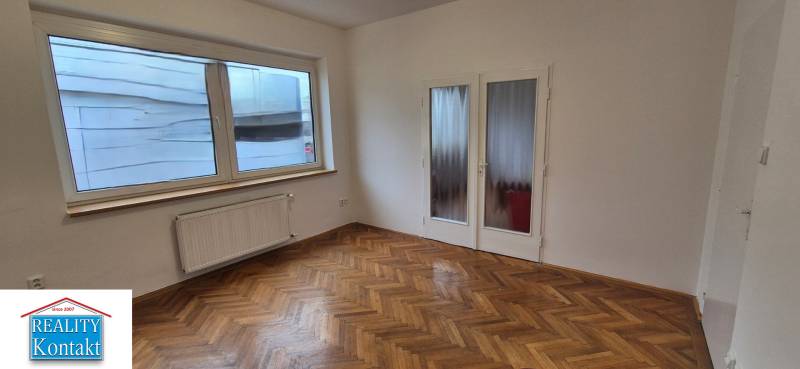 A room in a 3-room apartment with white walls and a wooden decor floor.