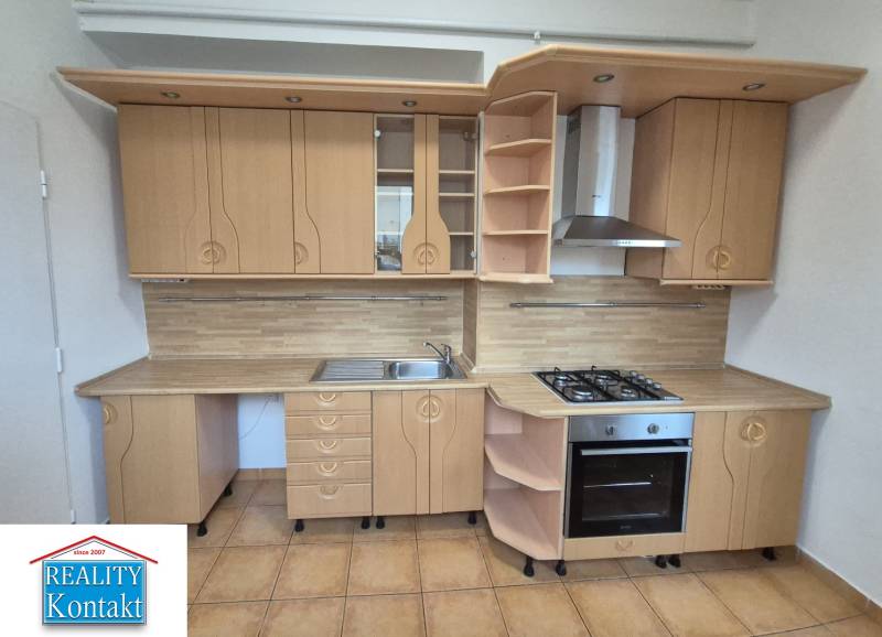 A kitchen with light wooden cabinets and appliances in a three-room apartment.