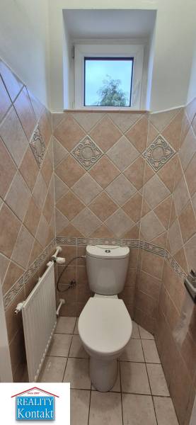 Bathroom with toilet in a 3-room apartment, tiled walls and a window.