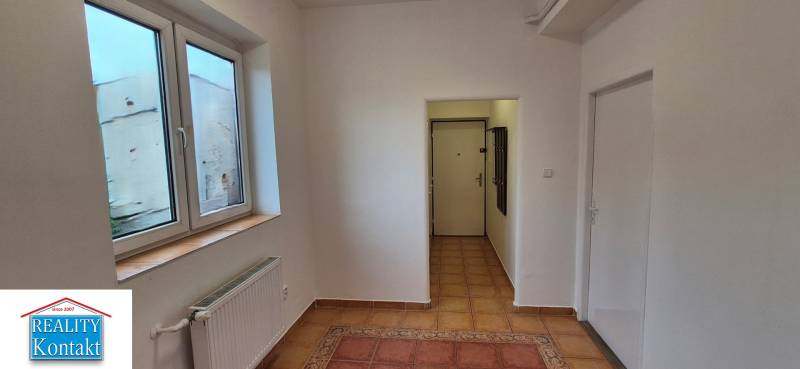 A hallway with a light coat of paint and a large window in a 3-room apartment.
