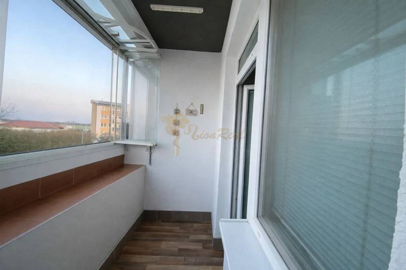 Glazed loggia in a 3-room apartment with a wooden decor floor.