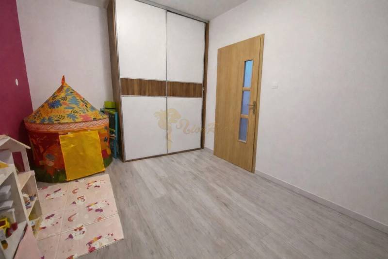 A children's room with a wooden decor floor and a colorful tent in a 3-room apartment.