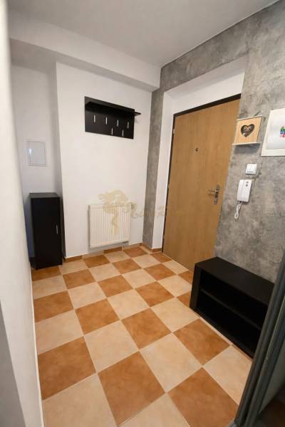 Hallway of a 3-room apartment with tiles, a coat rack, and wooden doors.