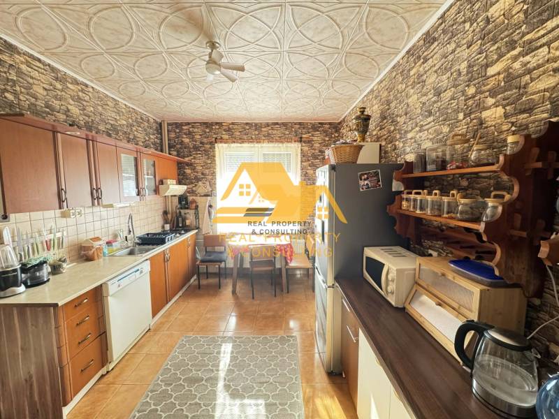 A kitchen in a family house with a wooden decor floor and stone walls.