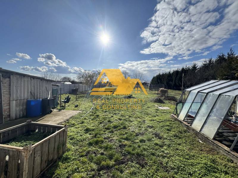 The garden of a family house in Tvrdošovce in Tvrdošovce with a lawn and a greenhouse.