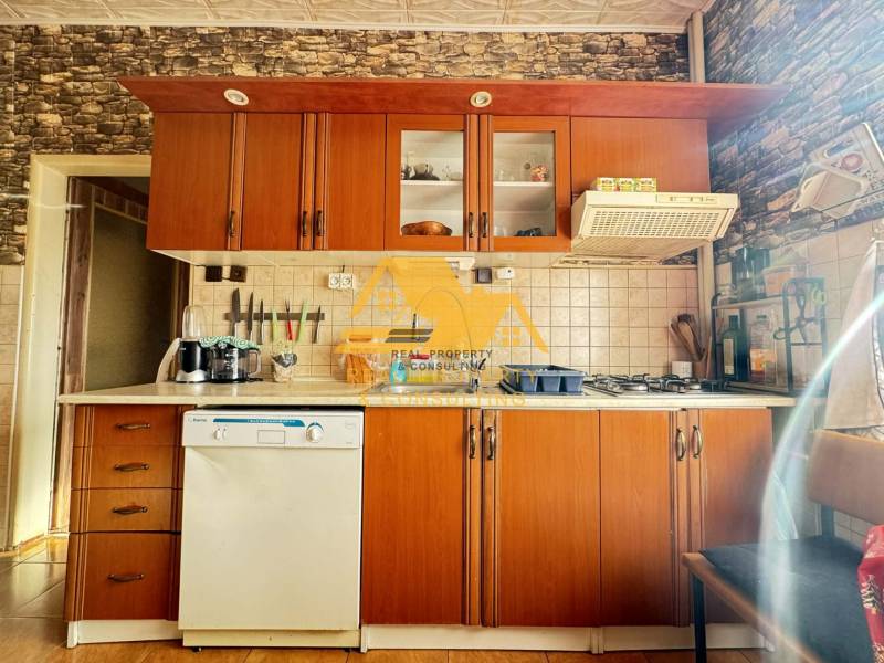 A kitchen in a family house with a wooden decor, equipped with appliances and kitchen cabinets.