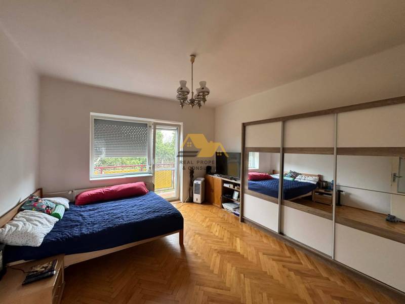 Bedroom in a family house with a bed, wardrobe, and floor with wooden decor.