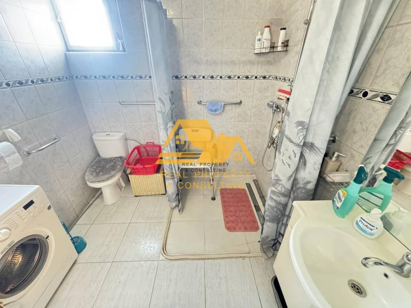 Bathroom in a family house with a washing machine, shower, and toilet.