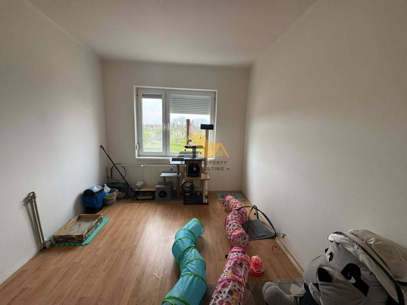 A room in a family house with a wooden decor floor and a view of the garden.