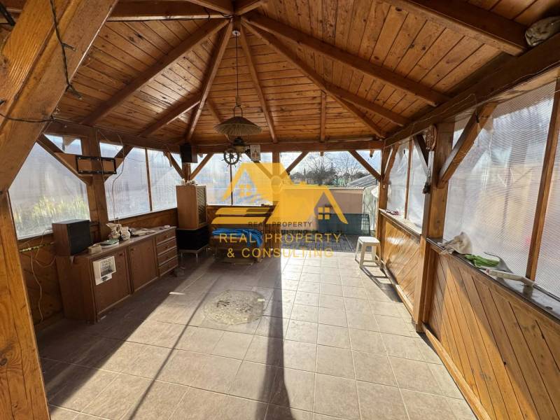 Wooden gazebo with a floor in a family house with a wooden decor, bright and spacious.