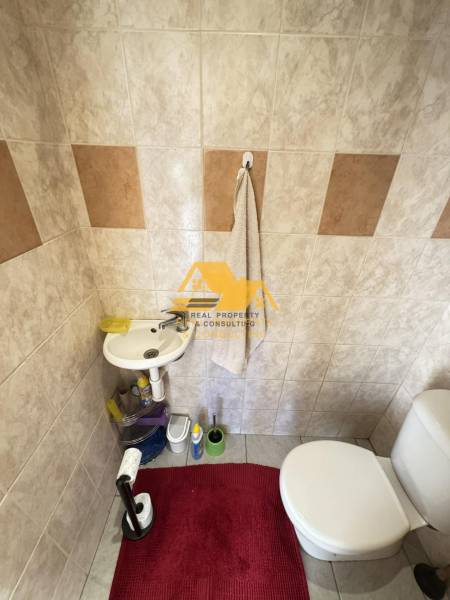 Bathroom with a sink and toilet, tiles combine light and brown shades.