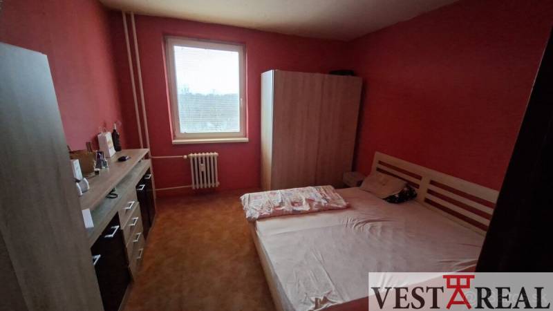 A bedroom with a bed and a wardrobe in a 3-room apartment, red walls.