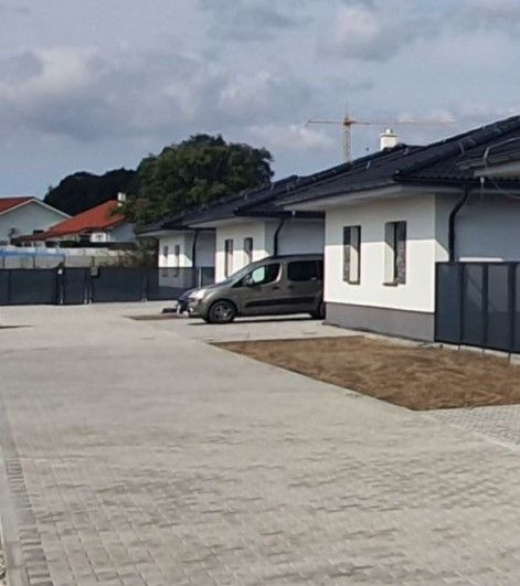 Family houses on Leknová Street in Láb with adjacent parking spaces and a fence.