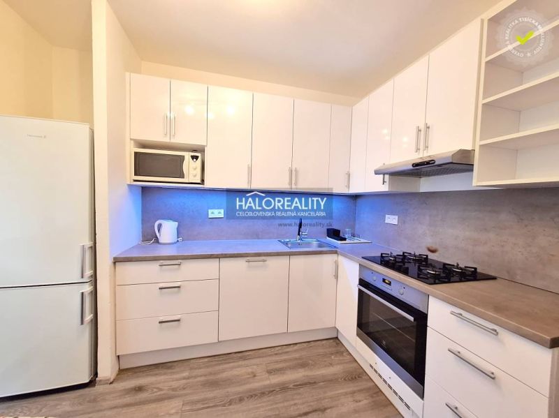 White kitchen in a 4-room apartment with wooden floor decor and modern appliances.