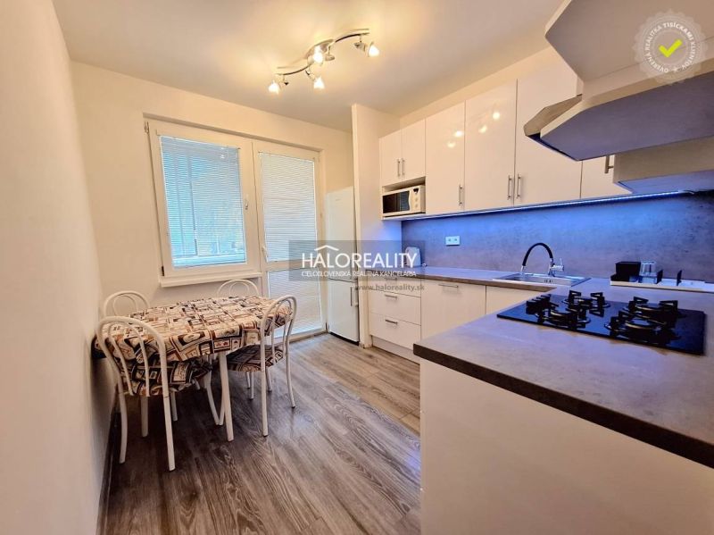 A kitchen in a 4-room apartment with a wood-patterned floor and a dining table.
