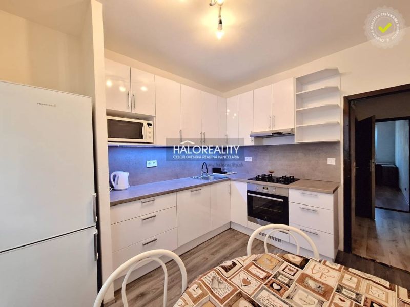 A kitchen in a 4-room apartment with a wood-patterned floor and white cabinets.
