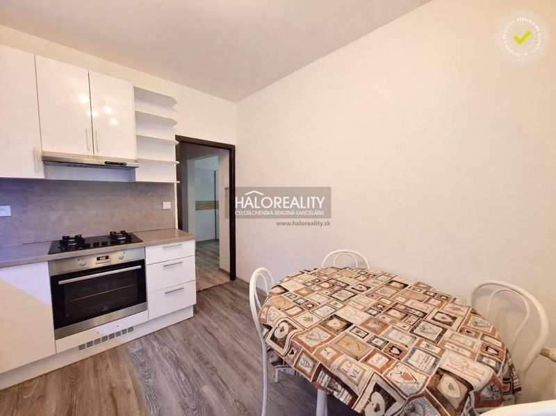 A kitchen in a 4-room apartment with a wooden decor floor and a dining table.