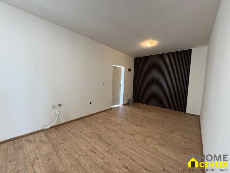 A room in a family house with a wooden decor floor and a bold black wall.